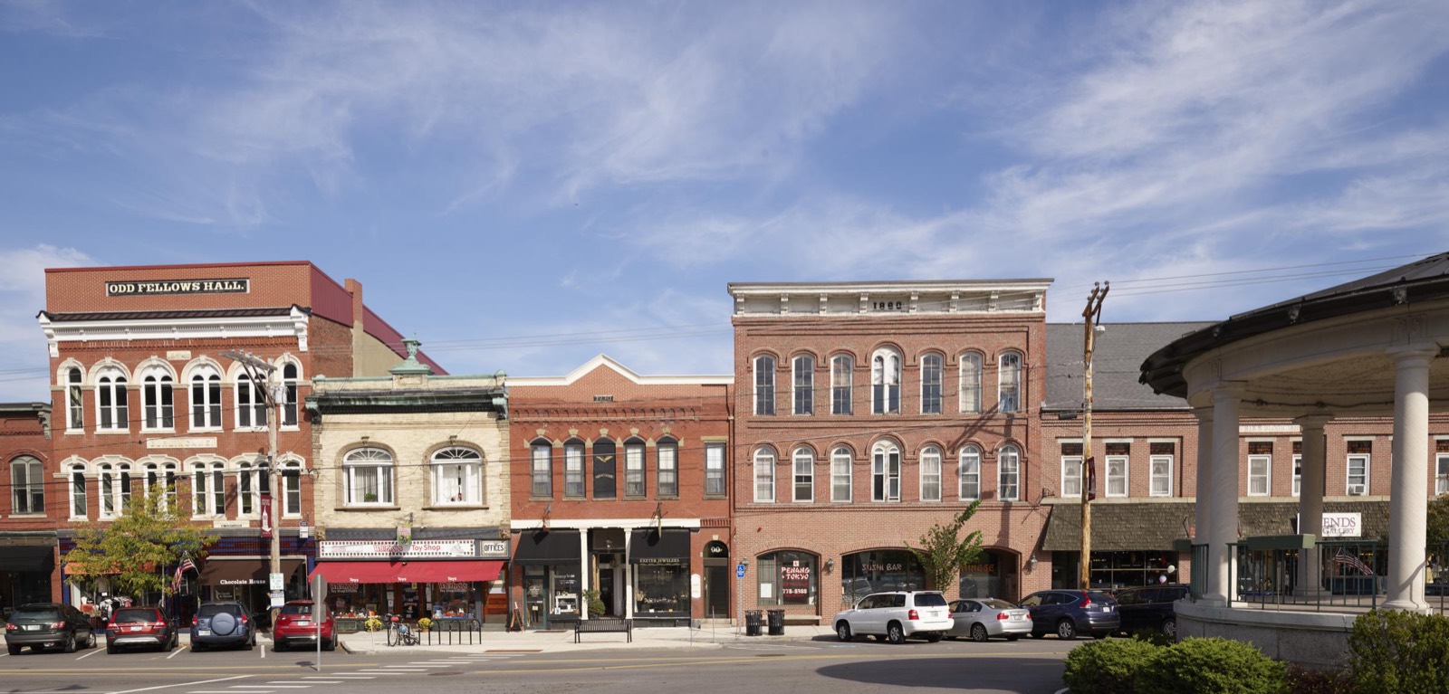 Red brick commercial buildings, including the Odd Fellows Hall, line downtown Exeter, New Hampshire, beside a columned bandstand.